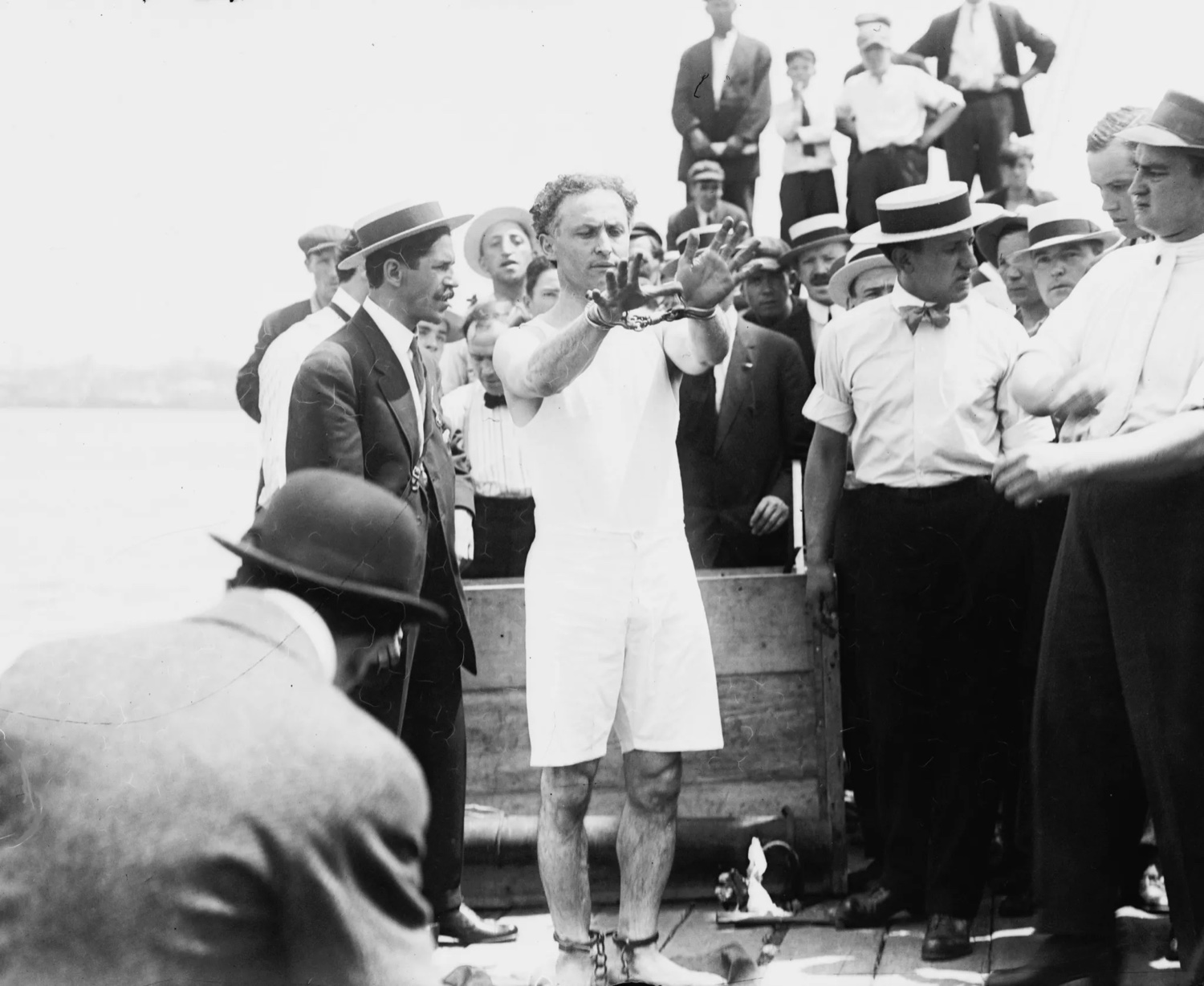 Harry Houdini menotté, entouré de la foule, avant une évasion (East River, New York, 1912)