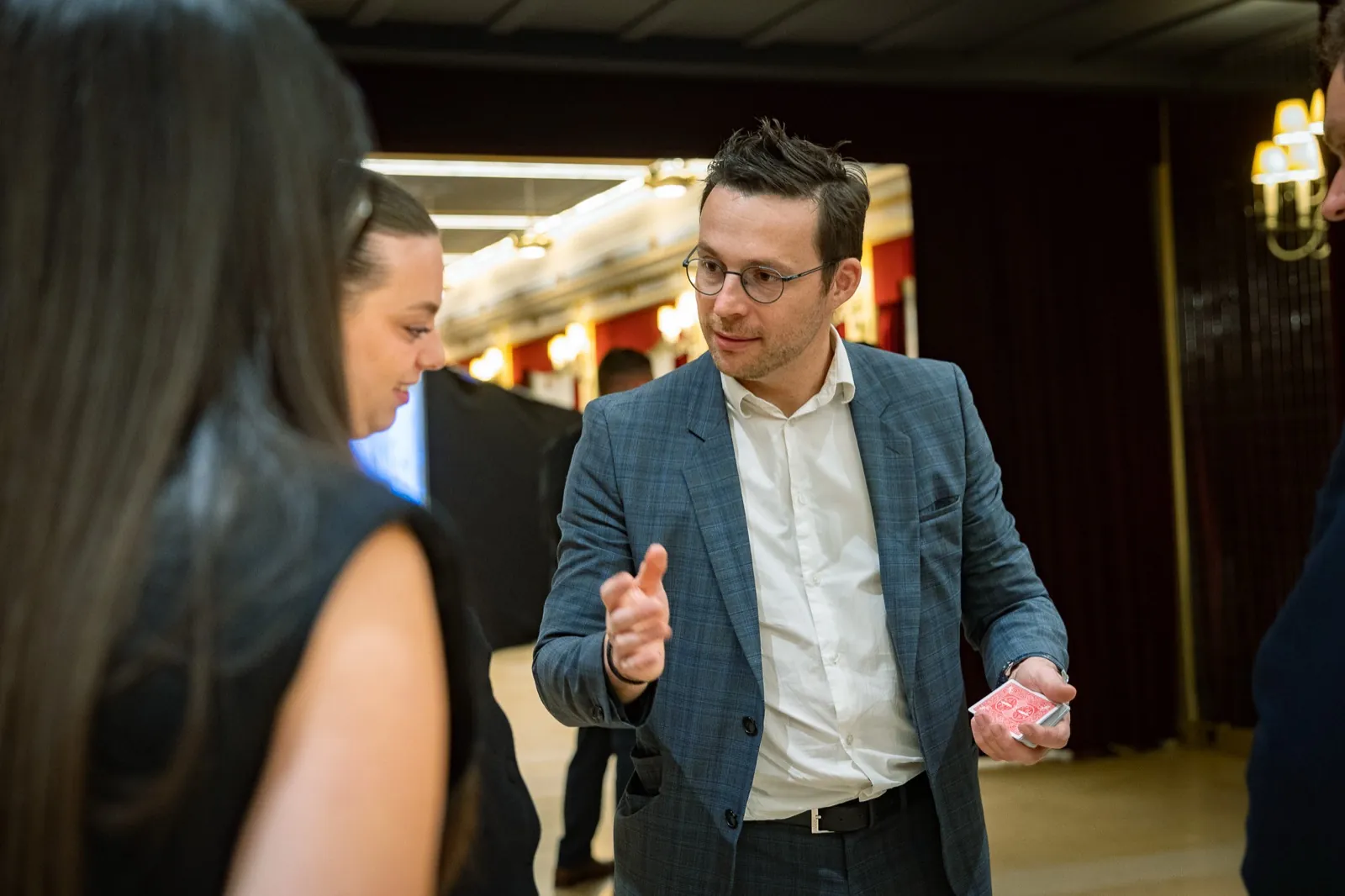 Hugo Marceau présente un tour de cartes à deux invitées pendant le cocktail d'un événement professionnel