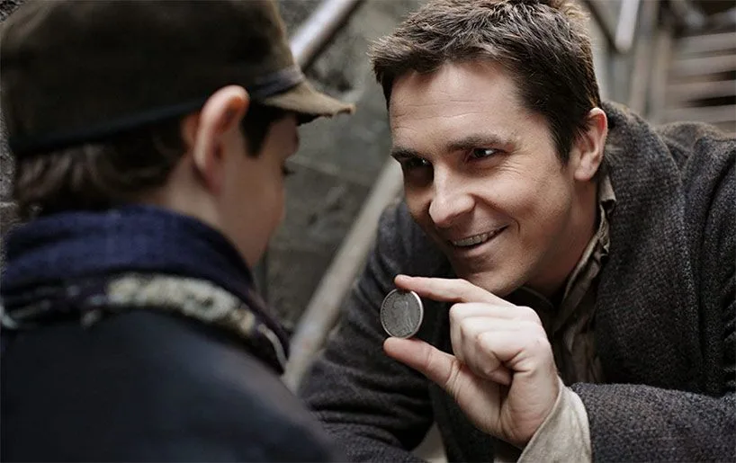 Christian Bale en Borden, souriant, fait un tour de pièce à quelques centimètres d'un jeune garçon