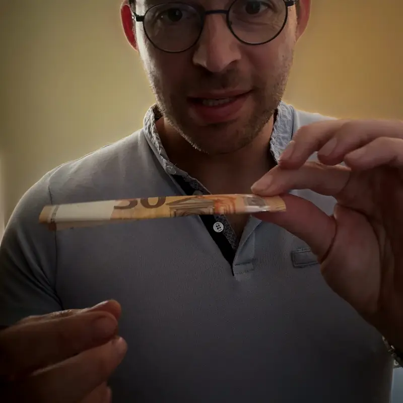 Hugo Marceau montre du doigt l'endroit de la papillote où la pièce est cachée dans le billet plié